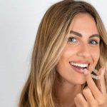 Woman holding a clear Invisalign aligner before placing it on her teeth.