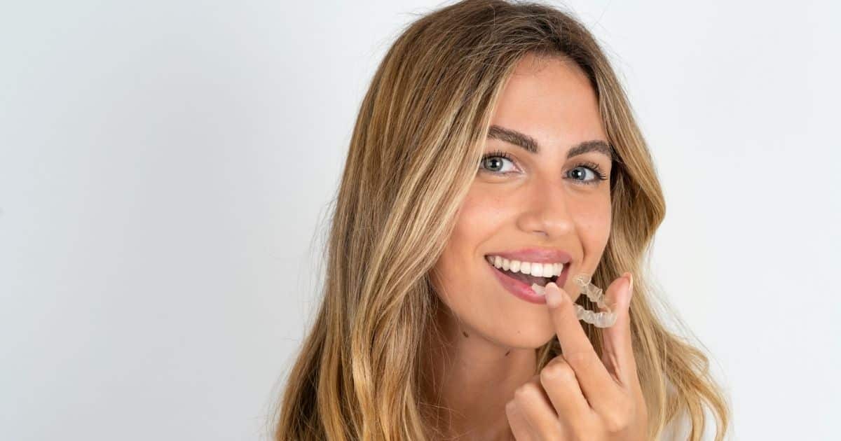 Woman holding a clear Invisalign aligner before placing it on her teeth.